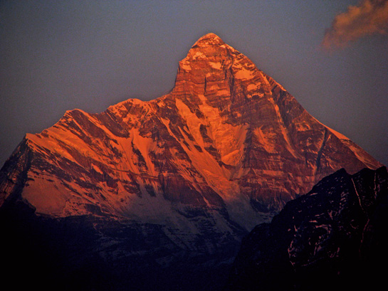 Nandadevi, India's second tallest peak, glows orange under a setting sun. To reconnect with his homeland after a devastating attack left him traumatised, the author undertook treks to Bandarpoonch, Nandadevi and Mt. Kailash.