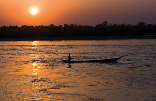 A fisherman fishing at sunset along the border of the Royal Bardia National Park in Nepal.